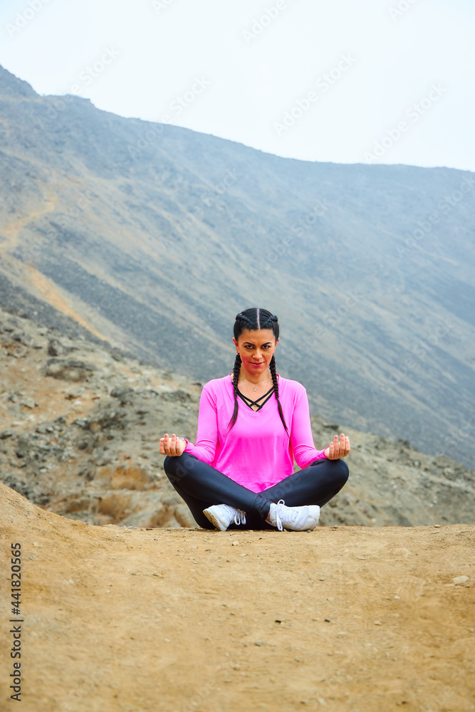 mature woman meditating on the mountain in sportswear