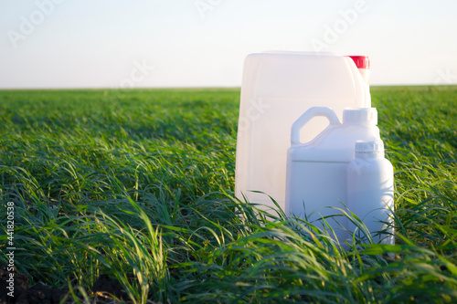 White canister against the background of agriculture, canisters from under different types of chemical products.