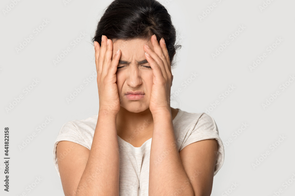 Unhappy millennial Indian woman isolated on grey studio background feel stressed suffer from migraine. Upset unhealthy young mixed race female struggle with headache, feel overwhelmed overwork. Unhappy millennial Indian woman isolated on grey studio background feel stressed suffer from migraine. Upset unhealthy young mixed race female struggle with headache, feel overwhelmed overwork.