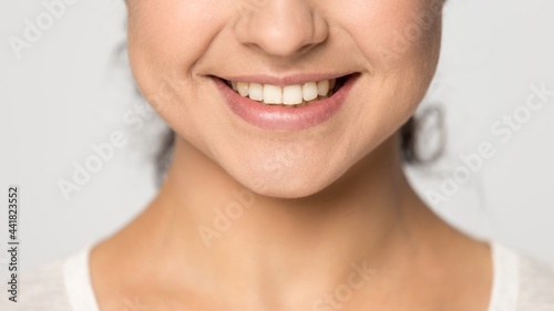 Crop close up of smiling Indian woman isolated on grey studio background show healthy even white teeth. Happy mixed race female client satisfied with good dental treatment. Oral hygiene concept.