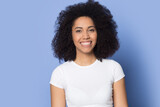 Headshot portrait of smiling African American woman isolated on blue background feel optimistic. Profile picture of happy biracial female look at camera show white healthy teeth. Diversity concept.