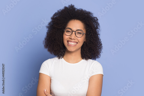 Headshot portrait of smiling African American woman in glasses isolated on blue background. Profile picture of happy millennial biracial female in spectacles have eyesight problem. Optician concept.