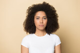 Headshot portrait of serious young African American woman isolated on yellow studio background look at camera. Profile picture of focused millennial biracial female client customer. Diversity concept.