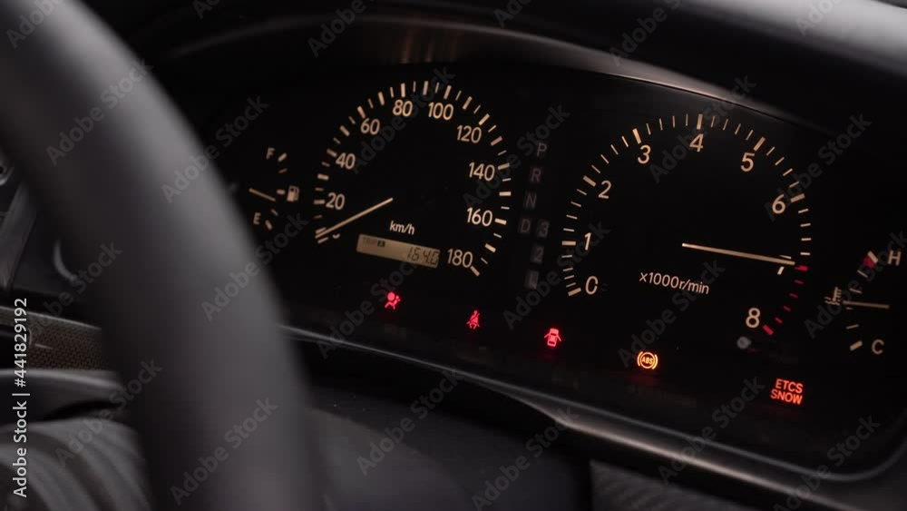 Car dashboard. The sports car revs on the spot. The driver keeps the