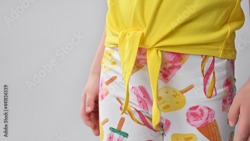 Close-up on a tie on a summer children's yellow cotton blouse, a little child demonstrates the details of clothing