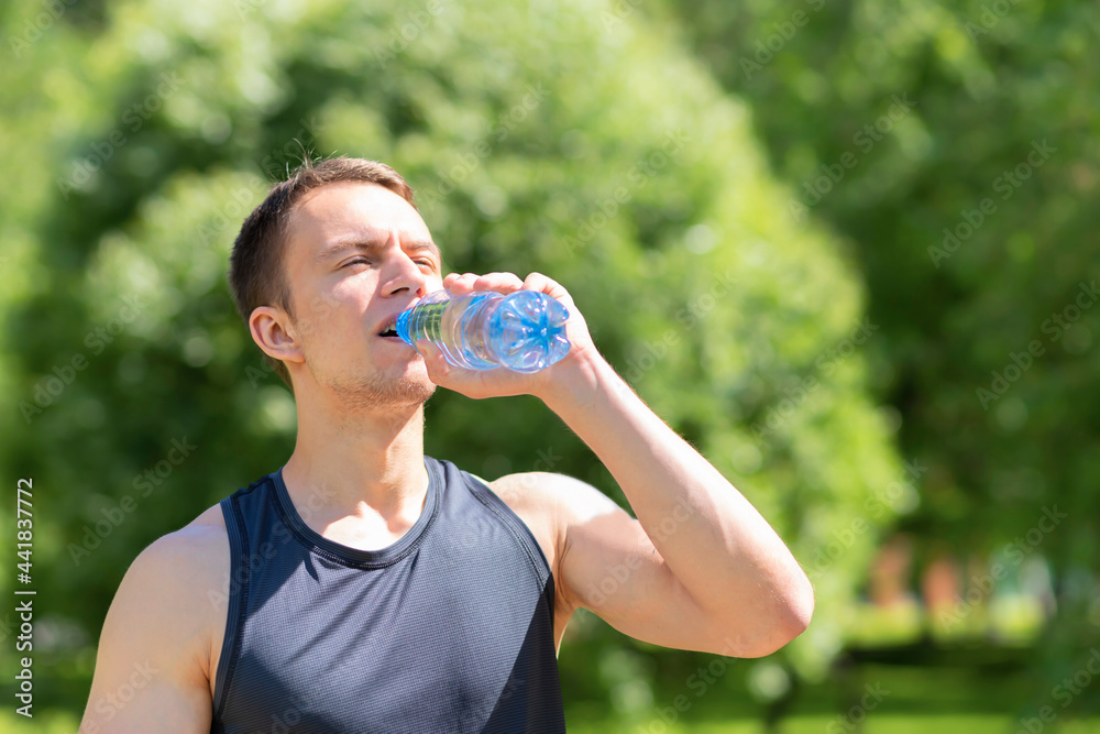 young male athlete with thirst drinking water from bottle after sports on sun in nature. guy with drink, beverage in hot sunny day. Man healthy lifestyle. prevention of dehydration, heat stroke young male athlete with thirst drinking water from bottle after sports on sun in nature. guy with drink, beverage in hot sunny day. Man healthy lifestyle. prevention of dehydration, heat stroke