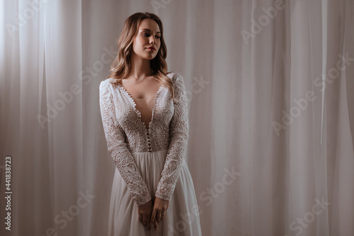 Beautiful brunette bride with light make-up in white dress  in an exquisite interior 