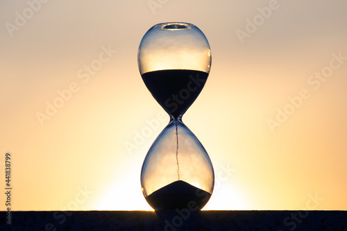 Hourglass counts the length of time against the background of the evening sun