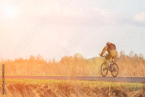 a male cyclist in motion rides along the road on a sunny day