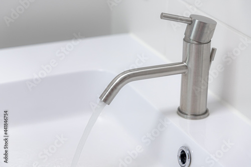 Hygiene concept  Selective focus of grey stainless water faucet with wash basin  Interior of bathroom with taps and sinks  Modern design of toilet  Sanitary ware with white colours. 