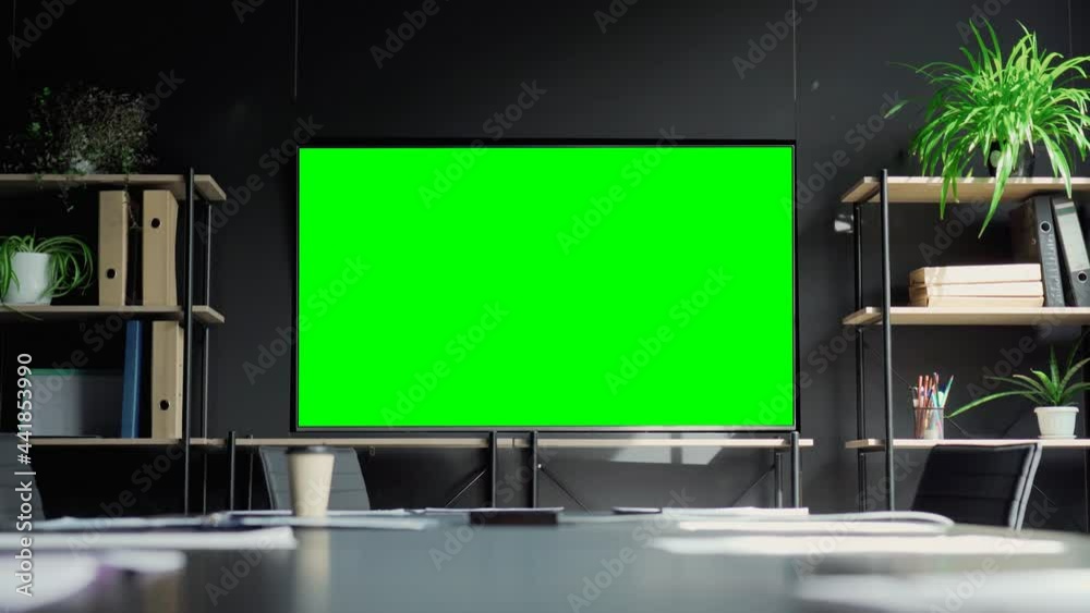 Meeting conference room with blank empty mockup tv screen monitor for advertising standing in modern contemporary office on black wall background. No people. Business technologies concept.