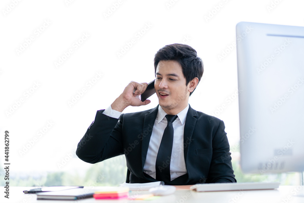 Smart and good looking Asian young businessman talking on the cellphone in the office. Smart and good looking Asian young businessman talking on the cellphone in the office.