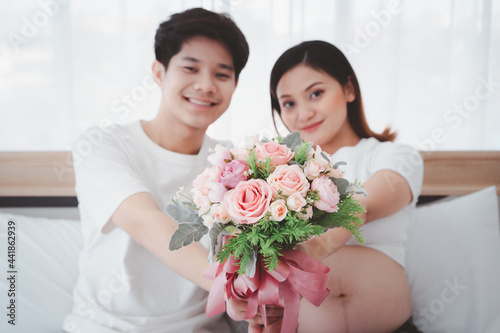 Cheerful Asian family, husband surprise his pregnant wife with a beautiful bouquet of flower close up.