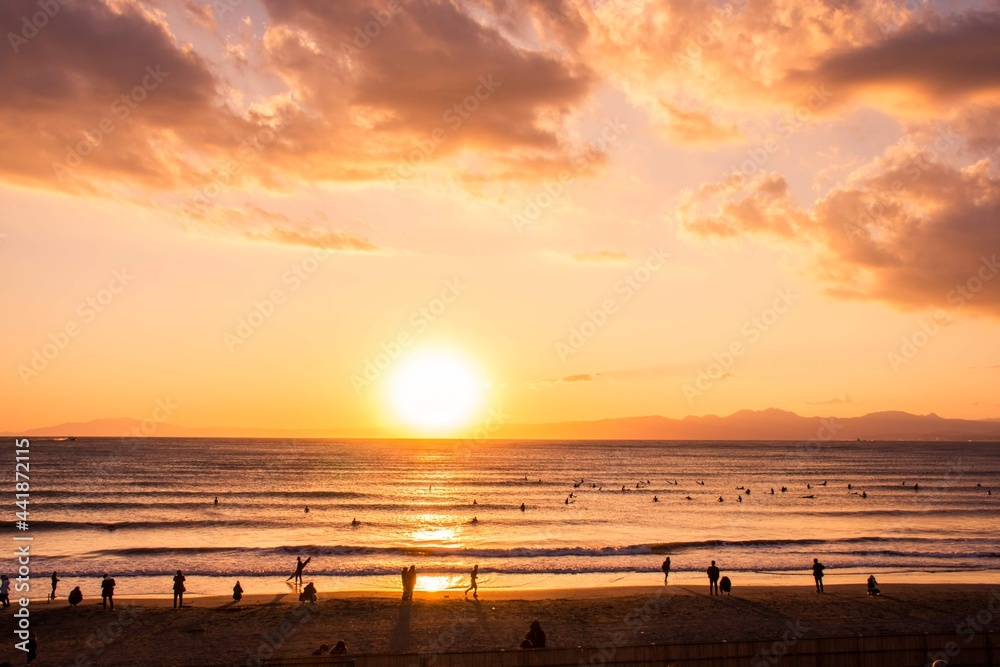 The romantic sunset and beach scene in summer with silhouette of People doing their activities on Beach at Sunset for recreational and relaxation. taken from Enoshima, Japan.