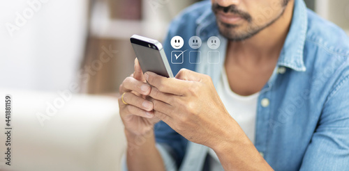 man pressing on mobile phone with happy icon for feedback review satisfaction service 