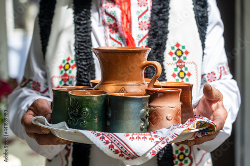 Moldovan man greets dear guests and invites them to drink homemade wine, close up photo