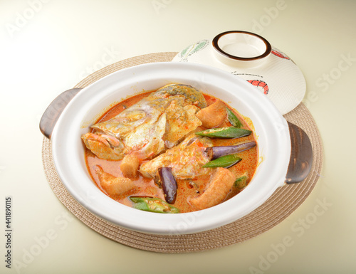 chef cook home style nyonya spicy curry grouper fish head with vegetables in big clay pot