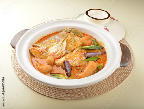 chef cook home style nyonya spicy curry grouper fish head with vegetables in big clay pot photo