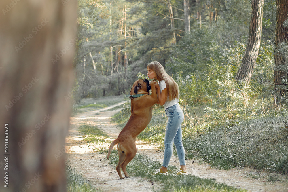 Naklejka premium Girl in a summer forest playing with dog