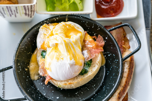 Egg benedict with bacon and sausage - delicious american breakfast