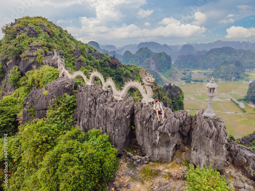 Male tourist on the background of Amazing huge dragon statue at limestone mountain top near Hang Mua view point at foggy morning. Popular tourist attraction at Tam Coc, Ninh Binh. Vietnam travel photo