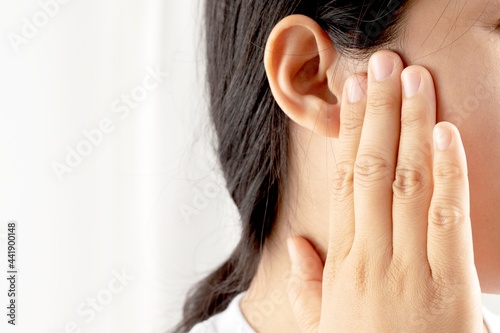 Young woman suffering from earache and tinnitus Causes of ear pain include otitis media and earwax buildup.
