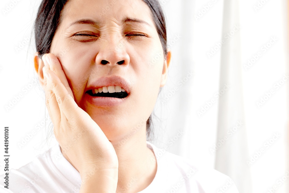 A woman touches her mouth in pain due to toothache or dental disease on her teeth. dentist concept A woman touches her mouth in pain due to toothache or dental disease on her teeth. dentist concept