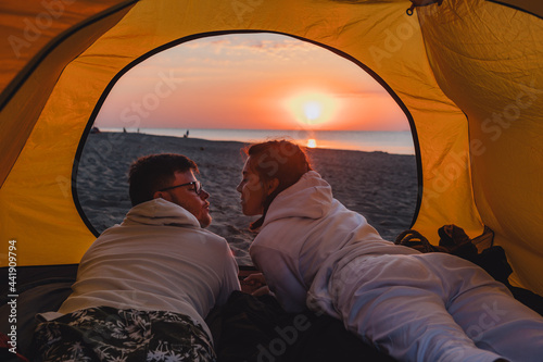 couple sleeping in camping tent looking at sunrise