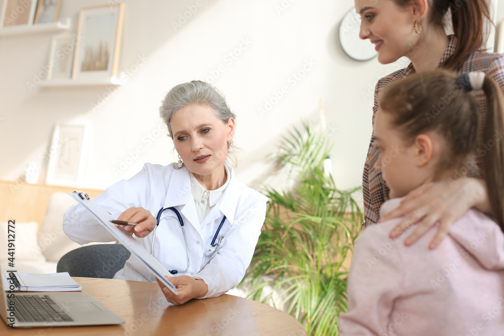 Fototapeta premium Mother and child in the doctor office meeting the pediatrician, they are sitting at desk in hospital.