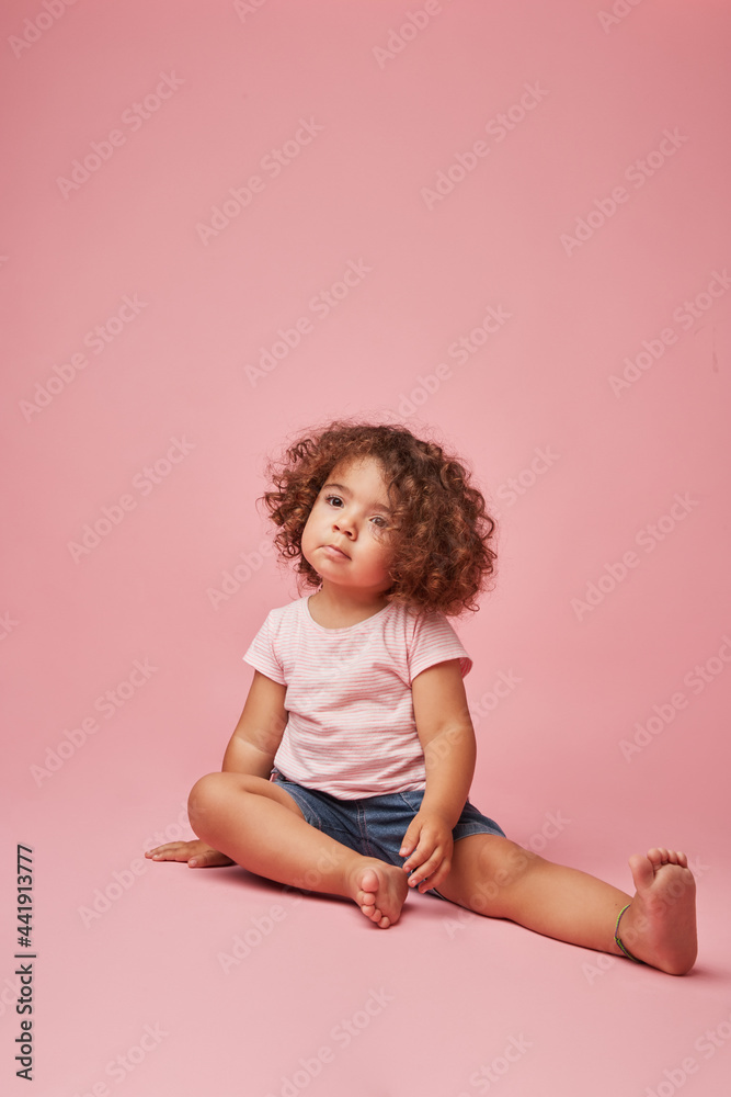 Charming kid sitting on pink background Charming kid sitting on pink background