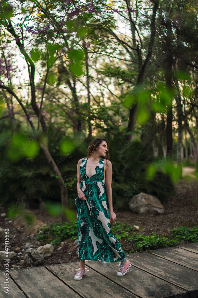 Stylish woman walking on boardwalk in lush park Stylish woman walking on boardwalk in lush park