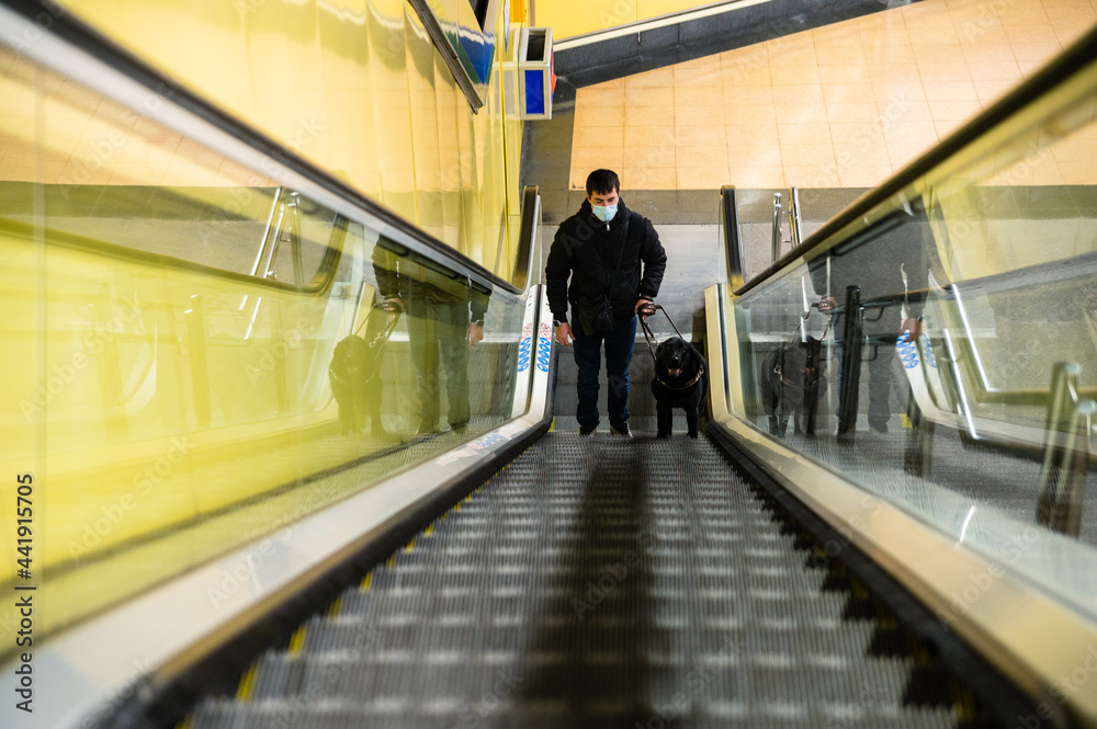 Blind man walking on escalator with guide dog Blind man walking on escalator with guide dog
