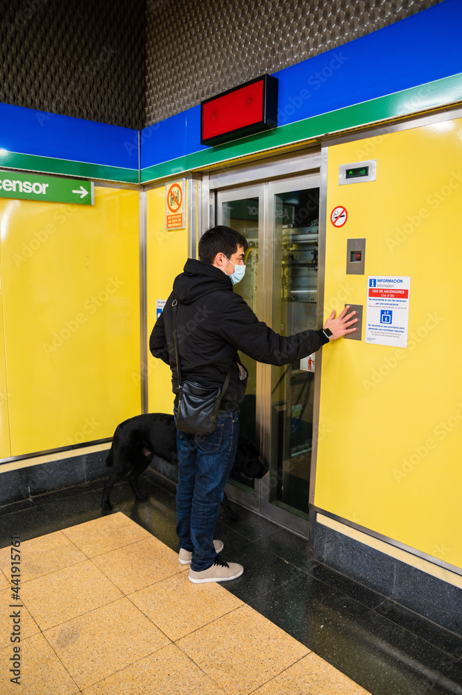 Blind man with guide dog pressing elevator call button Blind man with guide dog pressing elevator call button