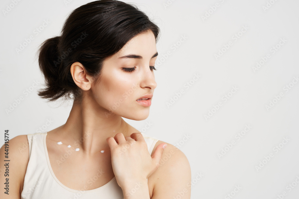 woman in white t-shirt applies cream to her neck clean skin dermatology