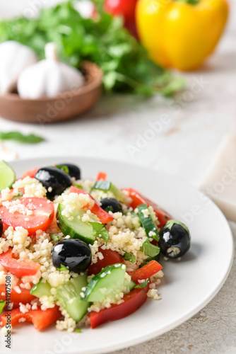Plate with couscous and vegetables on light background, closeup
