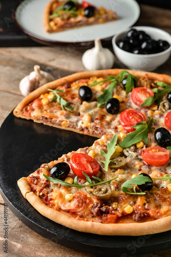 Board with tasty pizza on wooden background, closeup