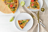 Plates with slices of tasty pizza on light wooden background