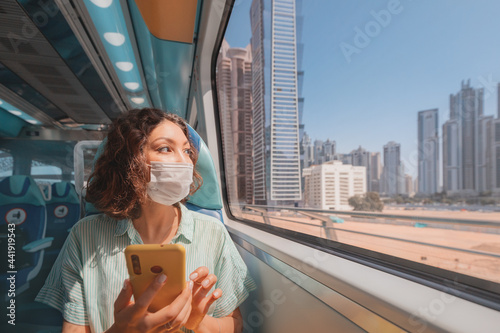 Canvas Print Woman in a protective medical mask rides the subway, holds a smartphone in her h