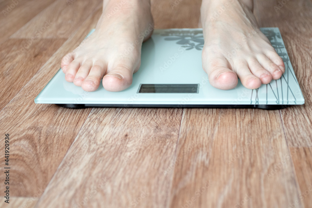 Female feet stepping on floor weigh scales. Female feet stepping on floor weigh scales.