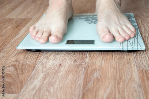 Female feet stepping on floor weigh scales.