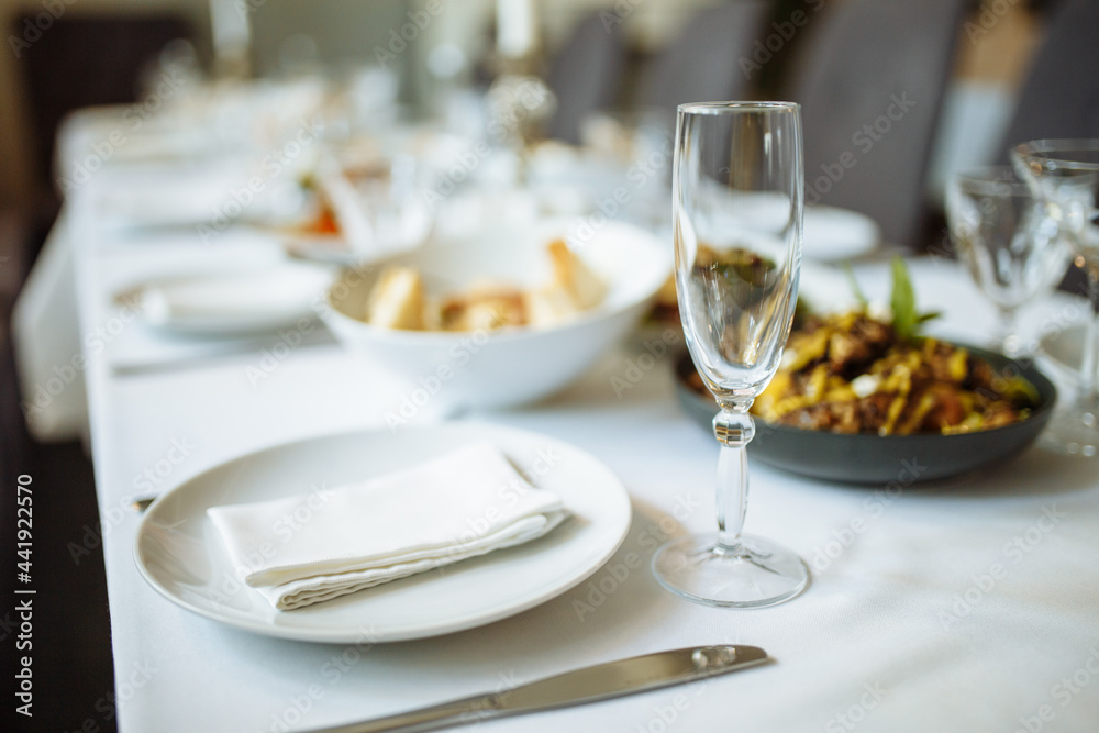 Ceramic tableware and luxury plate setting on table. Champagne glass, plate and napkin on the table before celebration. Served dinner table concept.