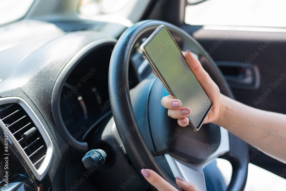 A faceless woman uses a mobile phone while driving a car. The girl uses the navigation in the smartphone