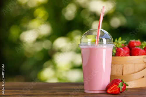 strawberry milkshake in disposable plastic glass on wooden table photo