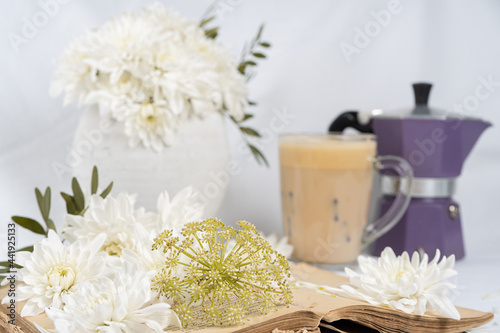 Still life with an old book  a cup of coffee and chrysanthemum flowers