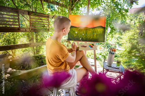 Foto Young female artist working on her art canvas painting outdoors in her garden