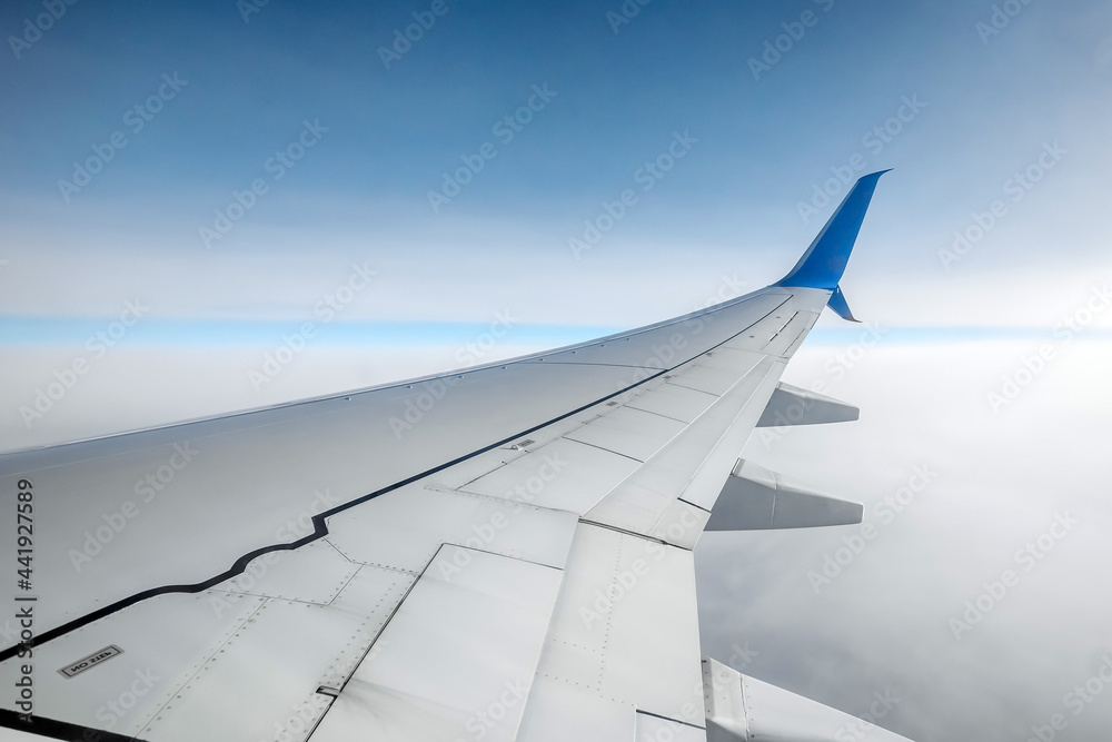 View from the window of a passenger plane above the clouds. International cargo transportation, air travel, transport, air travel, vacations. Copy space.