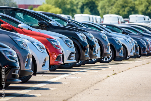 Row of brand new cars lined up outdoors in a parking lot. photo