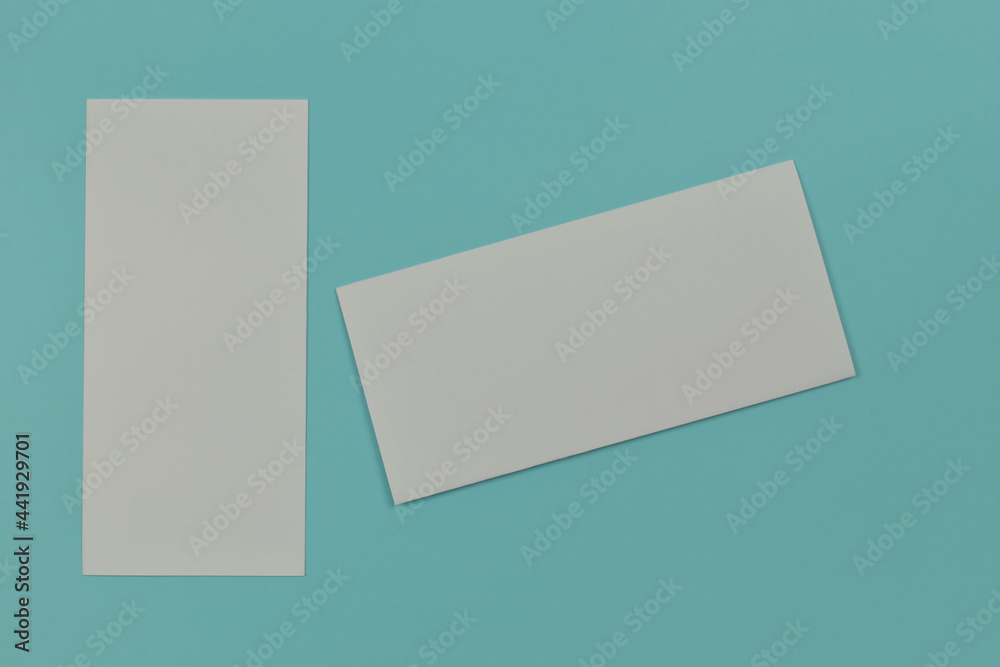Fototapeta premium Two folded blank paper leaflet on blue background with copy space.