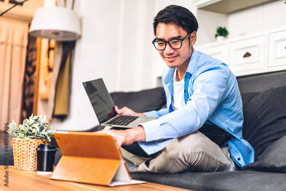 Young smiling asian man using laptop computer working and video conference online meeting with colleagues at home.Young creative man use tablet.work from home concept Young smiling asian man using laptop computer working and video conference online meeting with colleagues at home.Young creative man use tablet.work from home concept
