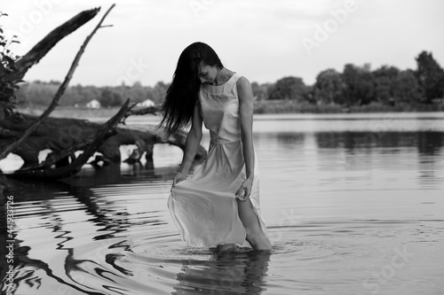 Beautiful young woman in white dress in the lake in black and white